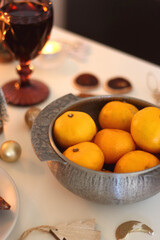 Various Christmas decorations, cookies, chocolate, nuts and tangerines, wine glasses and lit candles on the table. Holiday hygge at home. Selective focus.