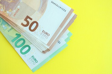 Big amount of one hundred and fifty euro money bills on yellow background
