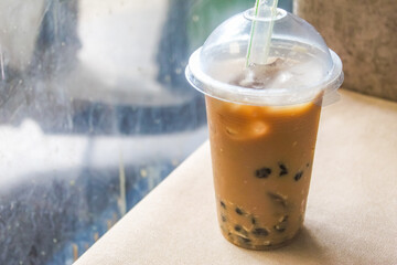 a glass of iced coffee containing boba or tapioca pearls in a plastic cup