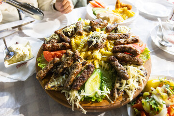 Mouthwatering platter of grilled meat, a popular Balkan dish, served with fries, vegetables, and cheese at the restaurant.