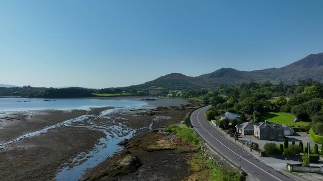 Adrigole Harbour, Beara Peninsula, County Cork, Ireland, September 2024. Drone pushes forwards along the Wild Atlantic Way along the coast road with the rugged Caha Mountains in the distance.