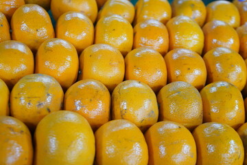 A neatly arranged display of ripe oranges, showcasing their vibrant orange color and shiny skin.