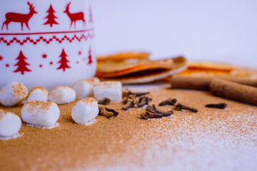 A pile of orange slices and cinnamon sticks on a white background. The oranges are cut in half and the cinnamon sticks are whole. Concept of warmth and comfort