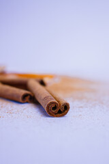 A pile of orange slices and cinnamon sticks on a white background. The oranges are cut in half and the cinnamon sticks are whole. Concept of warmth and comfort
