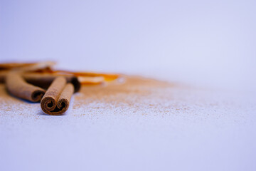 A pile of orange slices and cinnamon sticks on a white background. The oranges are cut in half and the cinnamon sticks are whole. Concept of warmth and comfort