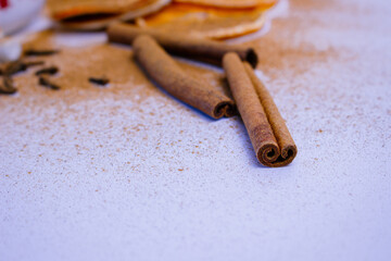 A pile of orange slices and cinnamon sticks on a white background. The oranges are cut in half and the cinnamon sticks are whole. Concept of warmth and comfort
