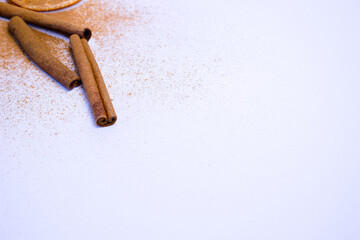 A pile of orange slices and cinnamon sticks on a white background. The oranges are cut in half and the cinnamon sticks are whole. Concept of warmth and comfort