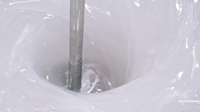 Industrial mixer creating whirlpool in white paint