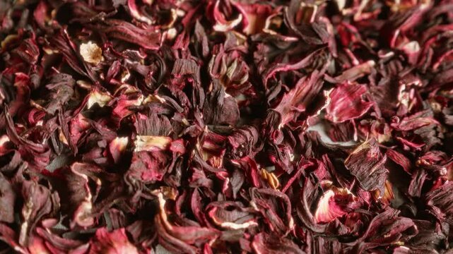 Dried hibiscus petals in closeup filling the frame showcasing their natural red and maroon colors suggesting herbal tea preparation