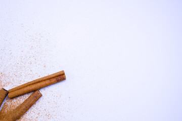 A pile of orange slices and cinnamon sticks on a white background. The oranges are cut in half and the cinnamon sticks are whole. Concept of warmth and comfort