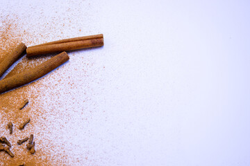 A pile of orange slices and cinnamon sticks on a white background. The oranges are cut in half and the cinnamon sticks are whole. Concept of warmth and comfort