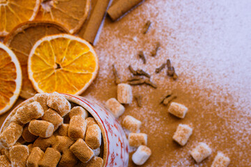 A pile of orange slices and cinnamon sticks on a white background. The oranges are cut in half and the cinnamon sticks are whole. Concept of warmth and comfort