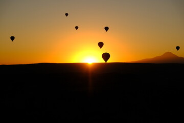 sunrise on horizon with hot air balloons in silhouette in Cappadocia, Turkey