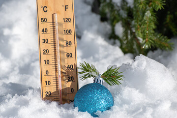 Christmas toy ball near tree and thermometer on natural snow in winter forest. Weather forecast for New Year and Christmas holidays. Frosty sunny day for happy free time in nature outdoor