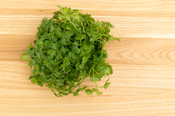 Fresh parsley leaves on the surface of a wooden kitchen cutting board