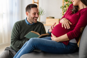 Happy pregnant couple reading a fairytale to unborn child. Family, parenthood child relation concept