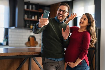Pregnant woman with her husband taking photos. Happy couple who can't wait to become parents
