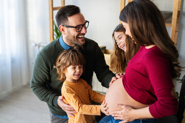 Sweet children and caring husband hugging, touching pregnant mom belly. Pregnancy, happy family