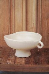 A minimalist white ceramic bowl stands on a rustic wooden surface. This stylish and functional bowl is perfect for serving salads, fruits, or snacks.