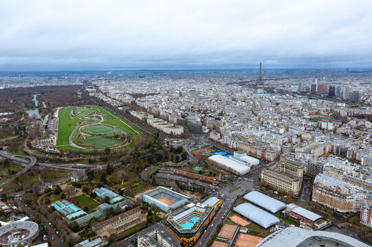 A breathtaking aerial view of Paris showcasing the verdant Parc des Princes and the iconic Eiffel Tower on the horizon, blending lush green spaces with the bustling urban architecture