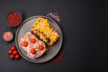 Sandwich with brioche, meat, melted cheese, ham, tomatoes, salt, spices and herbs
