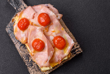 Sandwich with brioche, meat, melted cheese, ham, tomatoes, salt, spices and herbs