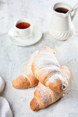 Croissants on table. Sprinkle croissants with powdered sugar. Concept of breakfast. Traditional French pastries.
