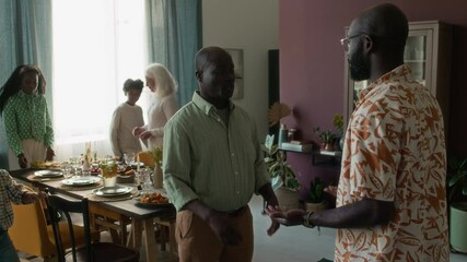 Senior father shaking hands with son and hugging him while visiting family with his wife for holiday lunch