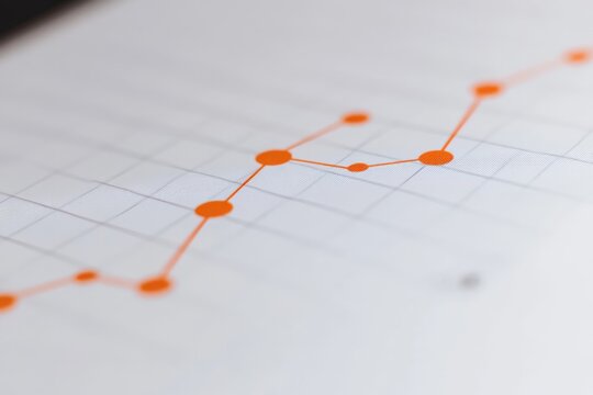 A close-up of a graph with an orange line on paper, illustrating an upward trend. It conveys a sense of growth, success, and positive progression.