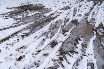 Tire tracks in the ice mud of winter in rural with snow. Off-road in frozen land. Landscape nature background.