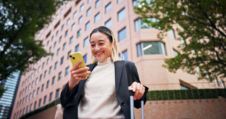 Business woman, smartphone and luggage on travel in city with contact, happy and low angle on urban sidewalk. Person, phone and corporate lawyer with booking taxi, networking and baggage in Japan