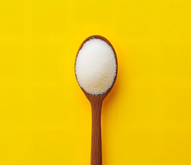 Spoon photo of white sugar powder on the spoon on a yellow background
