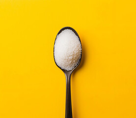 Spoon photo of white sugar powder on the spoon on a yellow background
