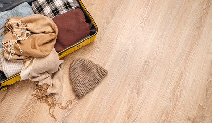 Packing a suitcase for a winter vacation, warm sweaters, winter hat, top view.