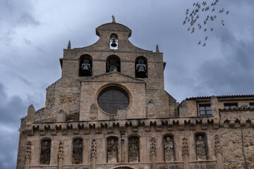 Monastery of San Salvador front facade in a stormy day with a bird flock on the sky. Oña village in Spain