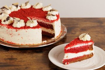Delicious tart with a slice of red velvet cake on white plate on a wooden table. Presentation of a rich and tasty modern dessert for celebrations such as weddings, birthdays, parties.