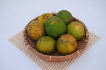 Orange fruit in wooden plate on bamboo mat. Selective focus and shallow depth of field.