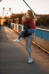 Joyful Couple Embracing as the Sun Sets Over a Scenic Bridge