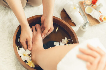 Woman indulges in blissful foot massage at luxurious spa salon while masseur give reflexology therapy in gentle day light ambiance resort or hotel foot spa. Quiescent