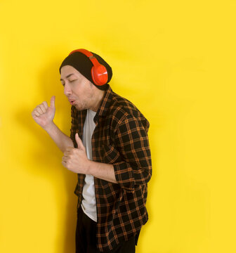 Young Asian Man With Beanie Hat Listening Music From Headphones And Enjoy Dancing With Thumbs Up