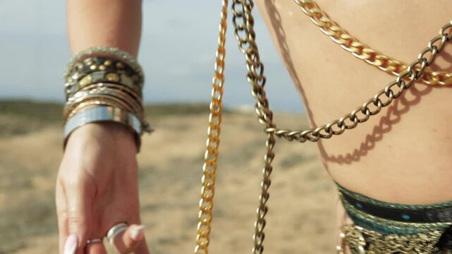 Belly dancer with long blond hair moves gracefully in the desert. She is wearing a gold skirt and top, and her body is adorned with gold chains and jewelry