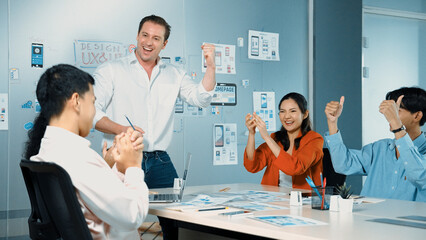 Obraz premium Diverse business team celebrate successful project by clapping hands and raising arm in the air. Group of happy corporate businesspeople smiling while sitting in business meeting. Manipulator.