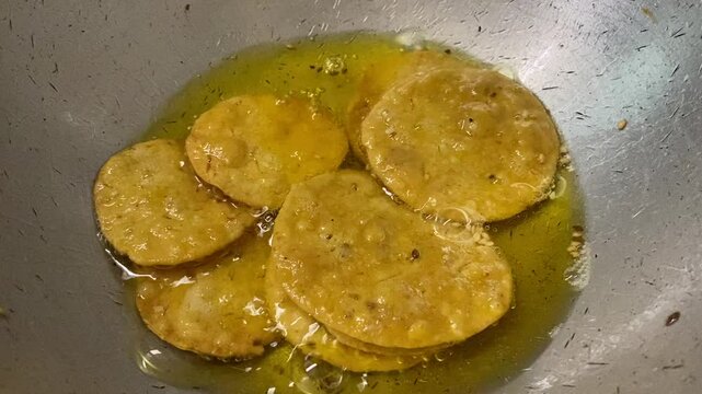Mathris sizzling in hot oil in a deep pan, their surfaces bubbling as they transform into golden, crispy discs.