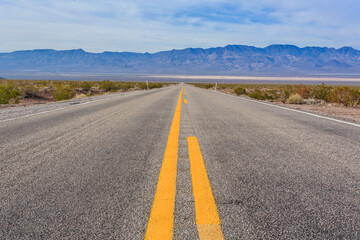 A long, empty road with yellow lines and a blue sky in the background