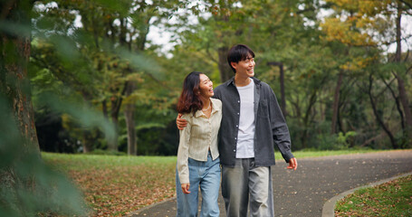 Asian couple hug, laugh and walk at park for holiday, funny joke or sightseeing together. Japanese man, woman and embrace outdoor on date for romantic connection, love or happy to travel on vacation