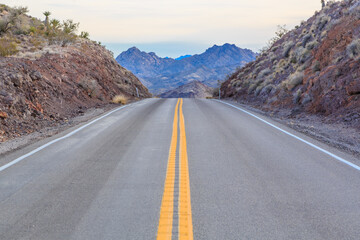 A long, empty road with a mountain range in the background