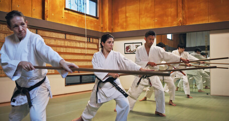 Dojo, class and Aikido training in gym with wood sword Japanese martial arts and fight exercise in...