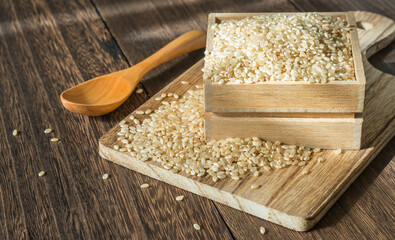 Japanese brown rice in a wooden container on a cutting board