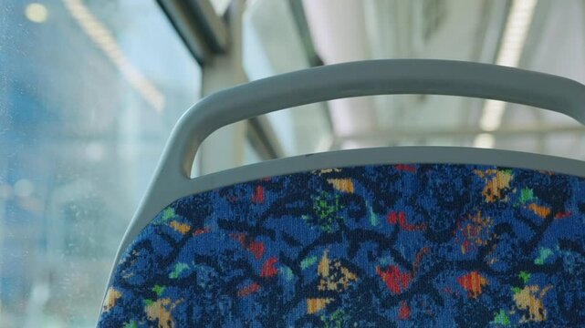 Close up on bus seat during a ride in the city on sunny summer day outside. Driving in city street passing traffic signs and buildings seen from window. Public transport in Tel Aviv Israel