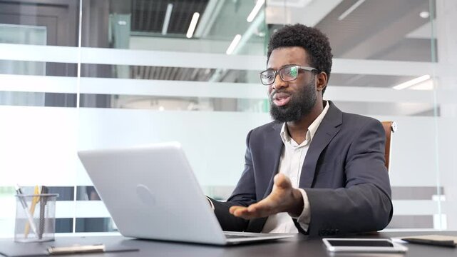 Upset african american businessman in formal suit receiving bad news on laptop while sitting at desk at a workplace in a business office. Concerned black man reads an unpleasant message on a computer
